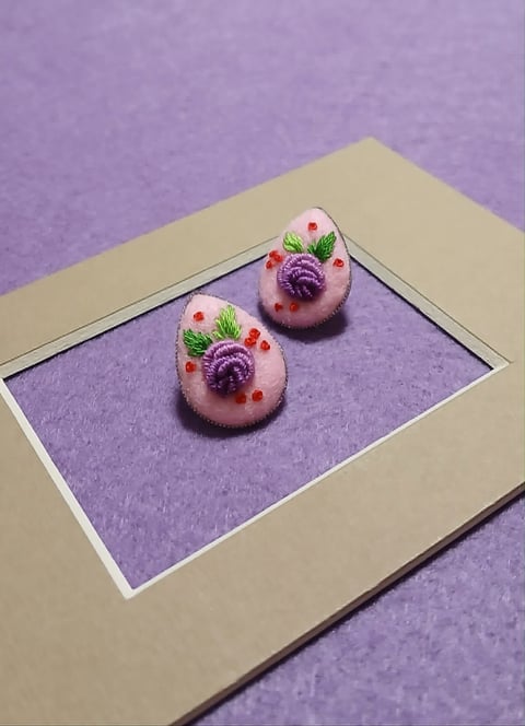 Two decorative pastel pink domes with purple flowers and berries on a purple framed display against a lavender background