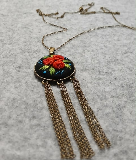 Hand-painted floral pendant necklace with red rose design on black enamel, featuring three dangling bronze chain tassels