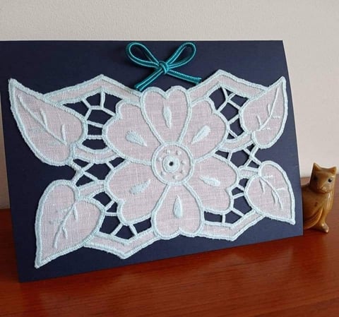 Handmade greeting card with white lace flower applique on navy background and turquoise bow