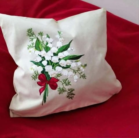 White decorative pillow with embroidered floral design featuring red flower and white blooms on red fabric background