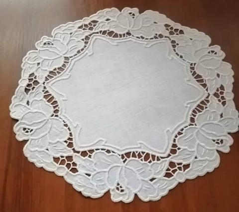 White lace doily with intricate floral cutout design on wooden surface
