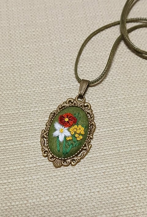 Vintage ornate pendant necklace with painted floral design featuring red, white, and yellow flowers on green background