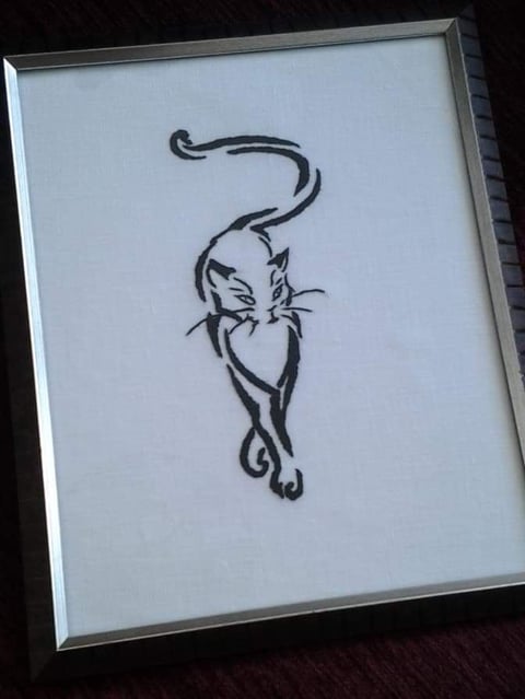Black ink sketch of a stylized cat with curved tail on white paper in a silver frame