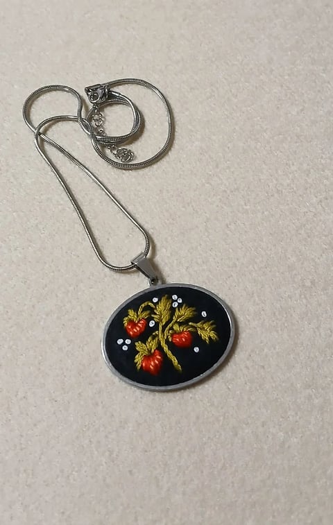 Silver snake chain necklace with oval pendant featuring hand-painted red strawberries and green leaves on black enamel background
