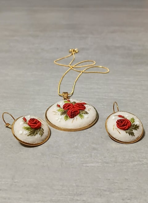 Gold jewelry set with three white porcelain pendants featuring red rose embroidery designs and matching chain necklace