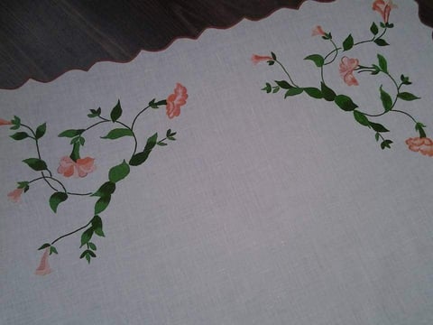 Floral embroidery design with pink flowers and green vines on white fabric with dark scalloped trim