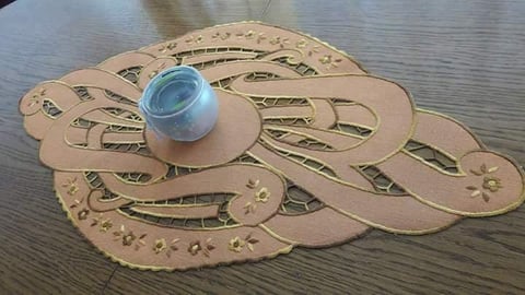 Blue glass orb sitting on layered cardboard spiral maze puzzle with cutout pathways