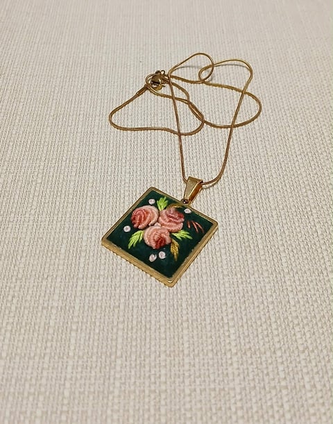 Vintage gold necklace with square enamel pendant featuring pink roses and green leaves on black background
