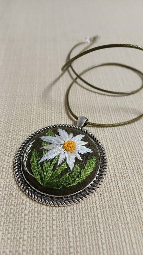 Hand-painted pendant necklace featuring a white daisy with yellow center on green background, attached to an olive cord
