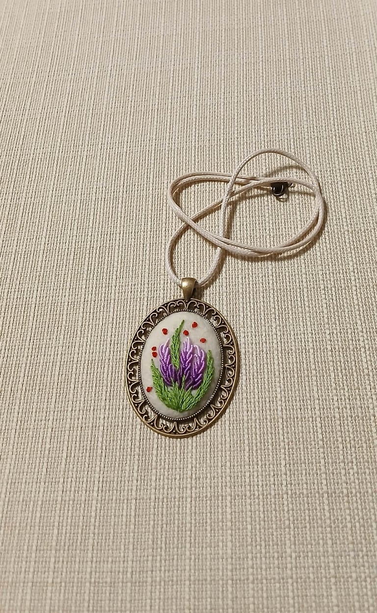 Ornate silver pendant necklace with purple lavender flowers and pink beads on white background