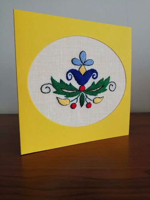 Handmade greeting card with yellow background and embroidered design featuring blue butterfly, heart, green leaves, and decorative berries on white circular panel