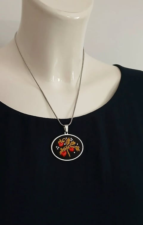 Silver necklace with colorful tree of life pendant on black garment, displayed on mannequin