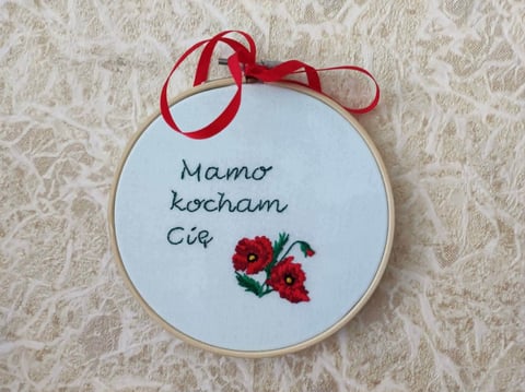 Embroidered hoop with red ribbon bow featuring handwritten Polish text Mamo Kocham Cie and red flowers