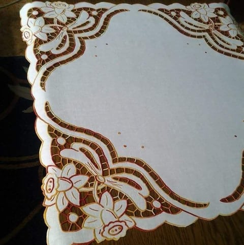 White linen cloth with ornate brown embroidered floral and geometric borders on two corners