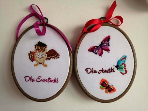Two embroidered oval hoops with ribbons: left features an owl with Dla Suelinki text, right shows butterflies with Dla Anetti text